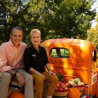 John and Pam McVay smile at the camera and sit in the back of an orange truck